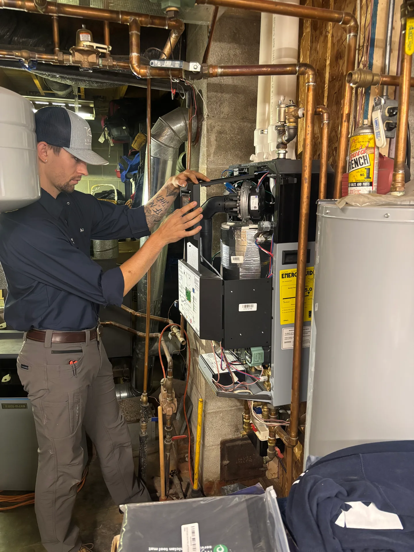 Boiler Control Service by Knauss Plumbing Knauss Plumbing owner checking boiler controls and copper piping in a mechanical room.