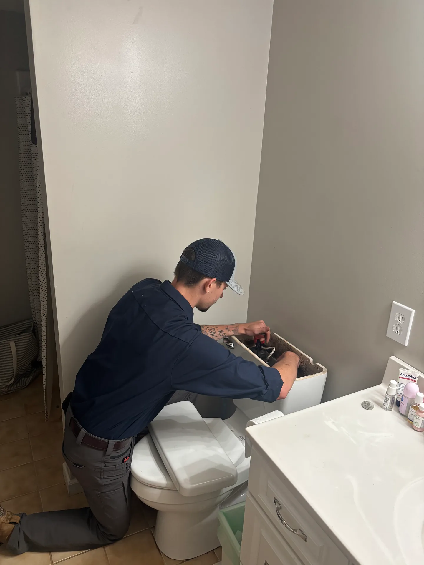 Toilet Supply Line Repair Knauss Plumbing owner working near a toilet supply line and bathroom shutoff.