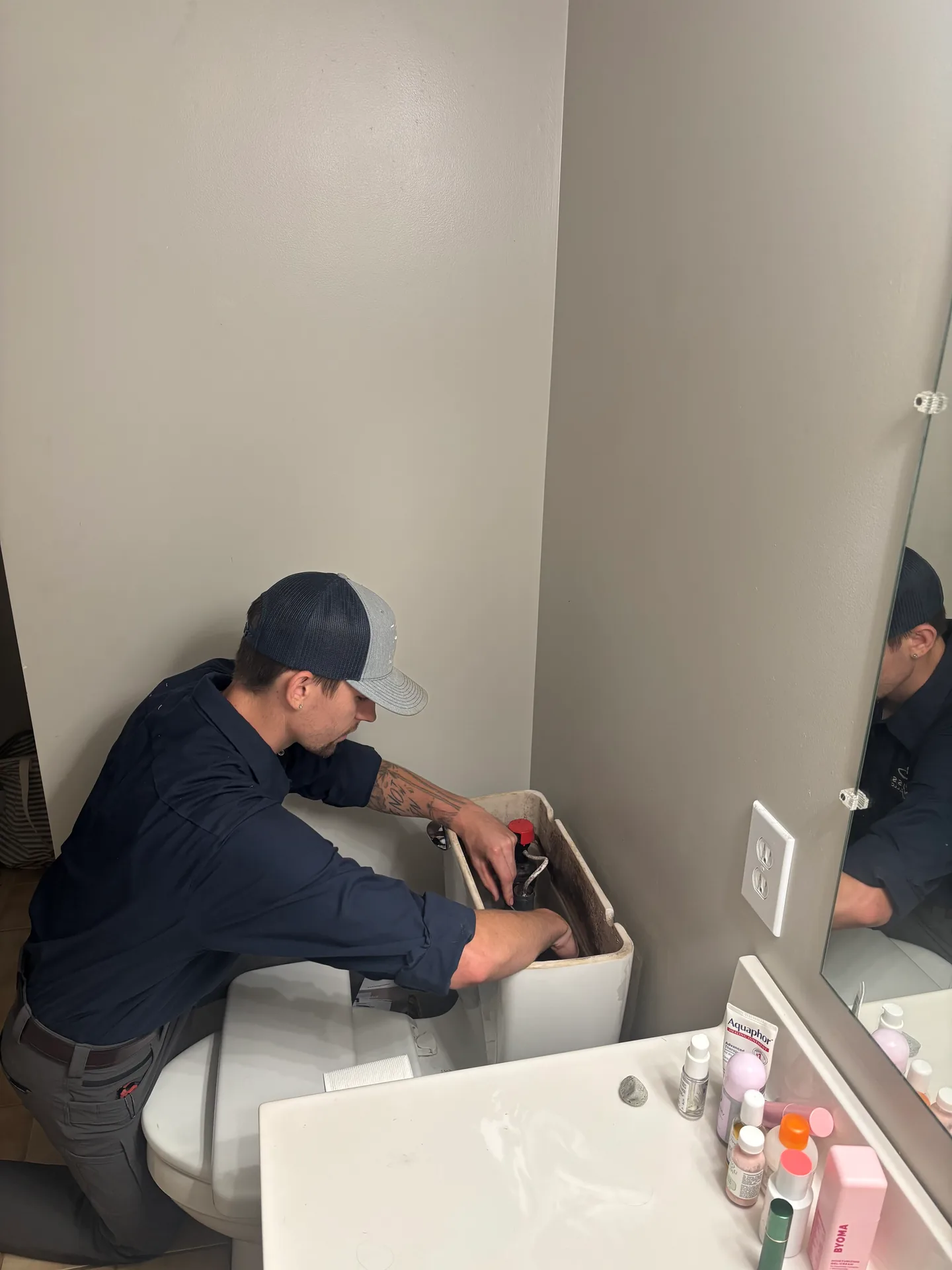 Toilet Tank Repair by Knauss Plumbing Knauss Plumbing owner repairing a toilet tank in a residential bathroom.