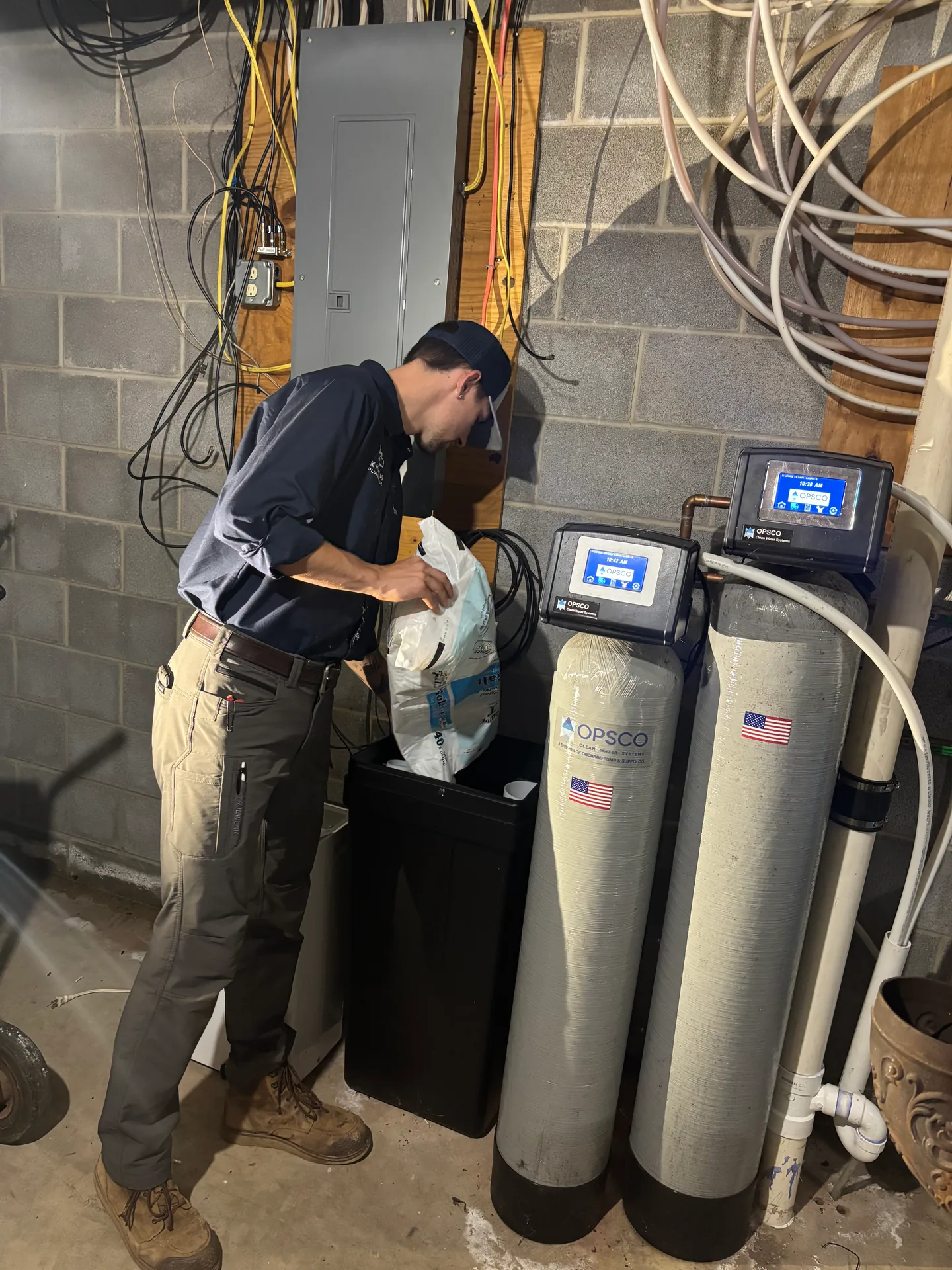 Water Treatment Service by Knauss Plumbing Knauss Plumbing owner servicing residential water treatment equipment in a basement.