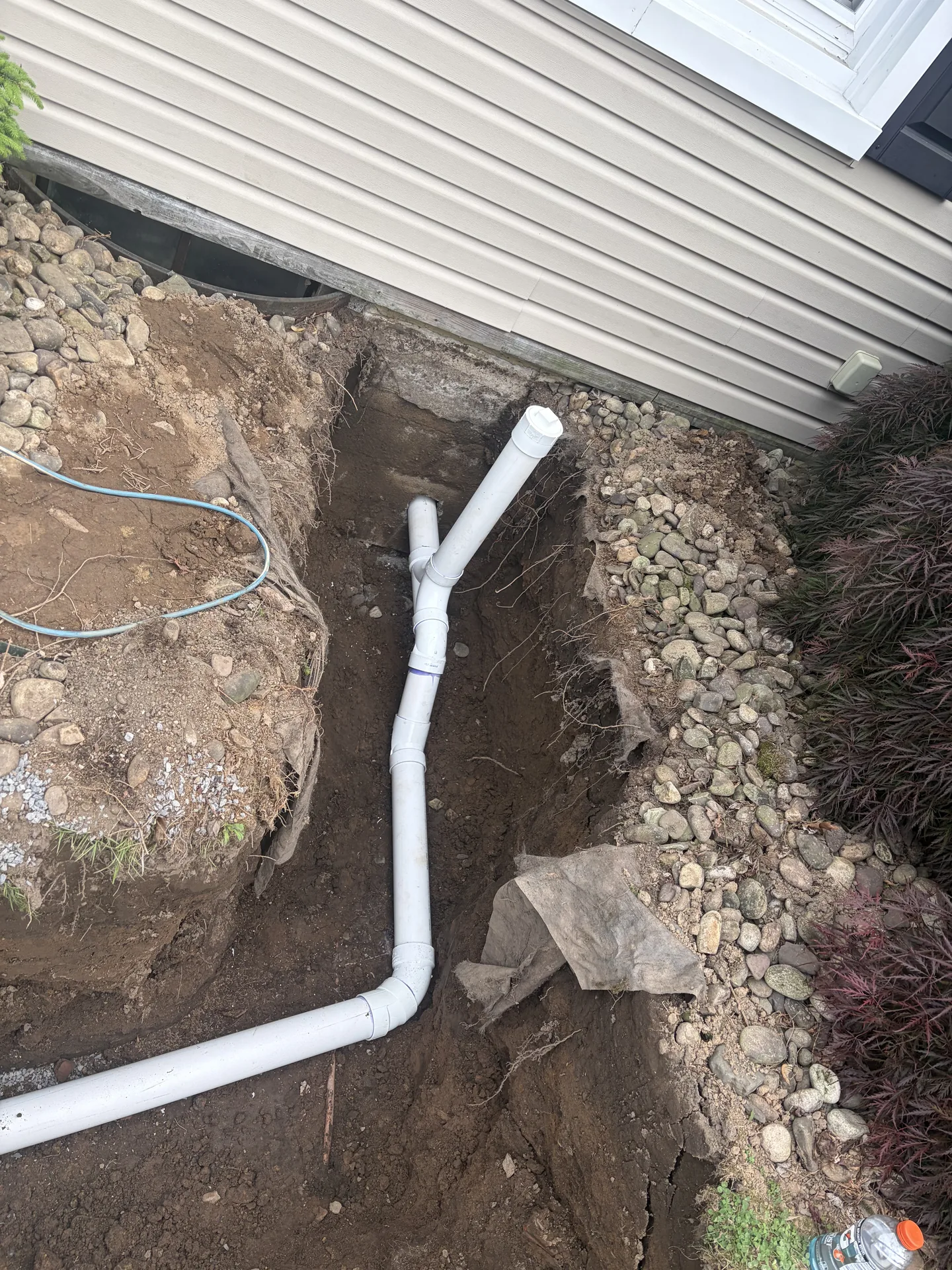 PVC sewer or drain piping installed in an exterior trench outside a home.